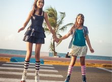 picture of a two girls riding roller skates on a road beside a sea