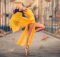 ballerina posing in the middle of street with falling yellow leaves