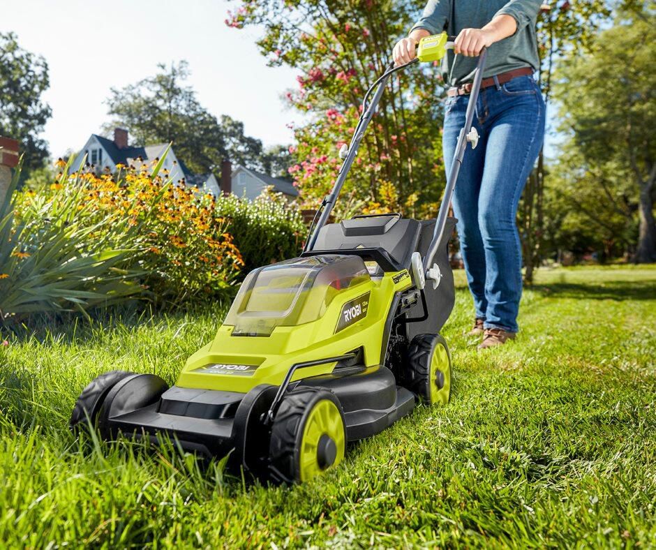 Woman cutting grass with electric mower