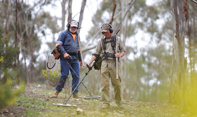 picture od two men walking in the mountain for gold prospecting with metal detectors and picks and shovels