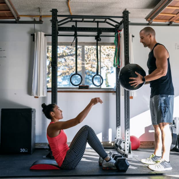 a couple working out together in their home gym with a cable machine