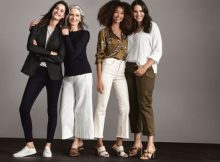 four women standing, wearing different styles of ladies pants and tops