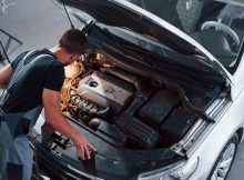 Mechanic inspecting car engine in a workshop