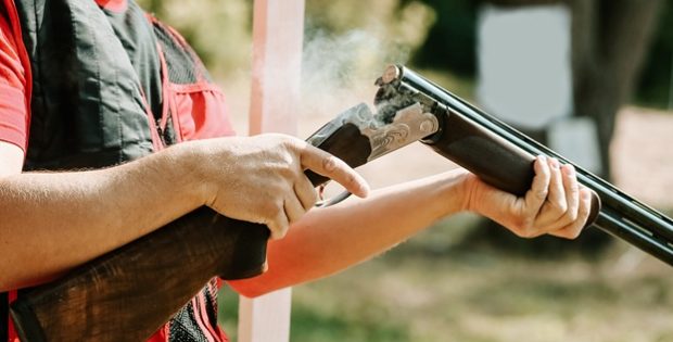man opens the shotgun bolt after one shot with smoke